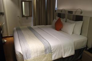 马累Beehive Premier的卧室配有一张带白色床单和橙色枕头的大床。