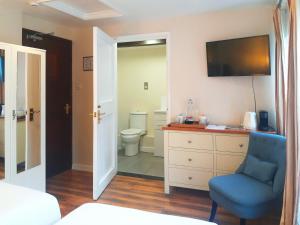 布罗肯赫斯特茅草屋酒店 的一间卧室设有卫生间和蓝椅