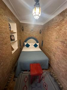 马拉喀什博纳尔庭院旅馆的一间小卧室,配有一张床和一张红色的桌子