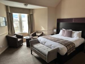 皮特洛赫里The Acarsaid - Pitlochry的酒店客房设有一张床、两把椅子和一扇窗户。