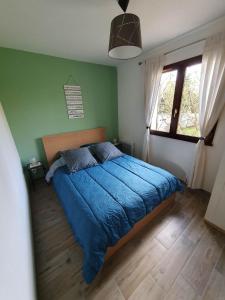 Le VaudreuilLa framboisette的一间卧室配有一张带蓝色棉被的床和窗户。