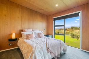 Otaki BeachBeachside Sanctuary - Otaki Beach Holiday Home的一间卧室设有一张床和一个大窗户