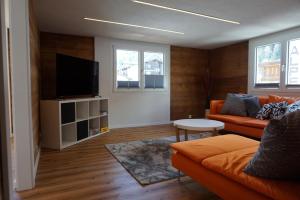 萨斯格伦德Rosenheim的客厅配有橙色沙发和平面电视。