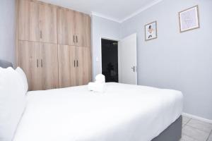 比勒陀利亚Comfy Hatfield Appartment的卧室配有白色的床和木制橱柜。