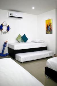 Puerto de GairaMigaloo Hostal Rodadero的白色墙壁客房的两张床