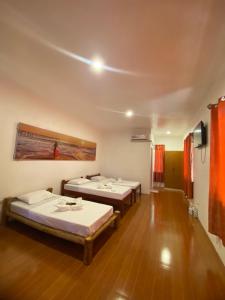 圣胡安Tahanan Resort的铺有木地板的客房内的两张床