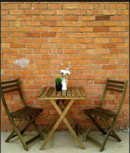 梳邦再也Cozy-SJ-Family Holidays/Work/BBQ/Tea-ceremony的砖墙旁的一张桌子和两把椅子
