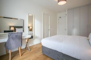 都柏林Grand Canal Square Apartments的一间卧室配有一张床、一张书桌和一面镜子