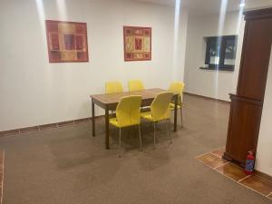 卡丹Apartmán Ateliér的一间带桌子和黄色椅子的用餐室