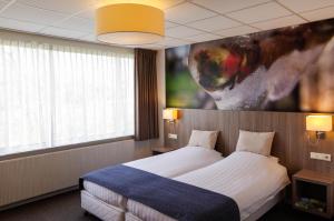 克拉亨堡Hotel and Restaurant van Saaze的酒店客房设有一张床,墙上挂有绘画作品