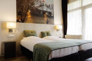 克拉亨堡Hotel and Restaurant van Saaze的酒店客房设有两张床,墙上挂着一张照片。