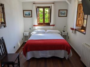 桑提亚纳德玛Posada Revolgo的一间卧室配有一张带红色毯子的大床