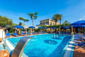 伊斯基亚Hotel Villa Svizzera Terme的一个带椅子和蓝伞的游泳池