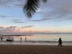 莫雷雷Quarto em frente à praia de Moreré的水中乘船在海滩上行走的人