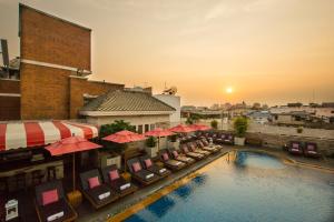 曼谷老友记酒店的享有酒店游泳池的景色,配有椅子和遮阳伞