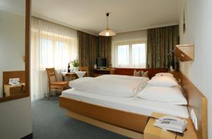 布雷根茨沃尔德地区奥Haus Alpina的酒店客房配有一张床铺和一张桌子,桌子上配有四柱床。