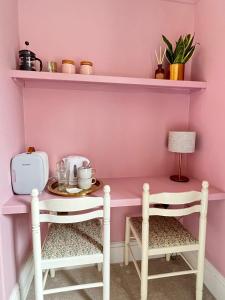 兰戈伦Riversdale House Bed & Breakfast的粉红色的房间,配有桌子和两把椅子