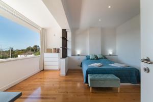 卡帕里卡海岸Caparica Dream Vila的一间卧室设有蓝色的床和大窗户