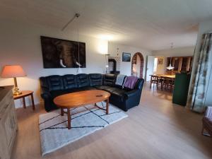 斯文堡Svendborg, Thurø ferievilla的客厅配有黑色真皮沙发和桌子
