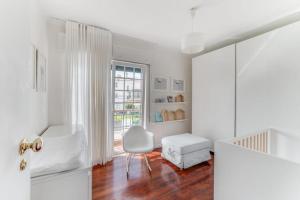 埃斯托利尔Casa da Praia的白色的客房设有白色的椅子和窗户。