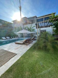 纳塔尔Pousada Laranja - Nova Administração的一座带游泳池的房子和一座带遮阳伞的庭院