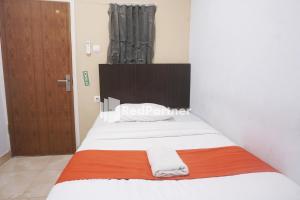 占碑市Tassa Homestay Syariah Mitra RedDoorz的一间卧室配有一张带橙色和白色毯子的床