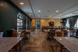 北榄Cozy Blu Suvarnabhumi的餐厅设有木桌、椅子和窗户。
