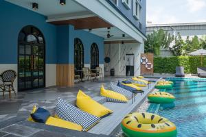 北榄Cozy Blu Suvarnabhumi的毗邻度假村的游泳池,泳池内提供黄色和蓝色枕头