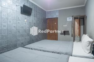 日惹Crown Residence near Tugu Yogyakarta Mitra RedDoorz的墙上有红色伙伴标志的房间的两张床