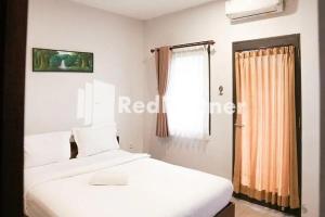 巴图Panorama İnn Residence Batu Mitra RedDoorz的卧室配有白色的床和窗户。
