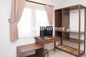 巴图Panorama İnn Residence Batu Mitra RedDoorz的客房设有书桌、电视和窗户。