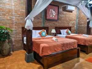 日惹纳尔姆苏月萨托诺旅馆的一间卧室设有两张床和砖墙