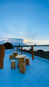 亭可马里KPN Trinco Holiday Resort的甲板上俯瞰水面的一组桌子和长椅