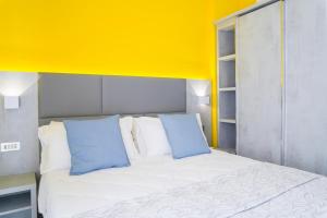 里米尼Hotel Mon Pays的一张带两个蓝色枕头和黄色墙壁的床