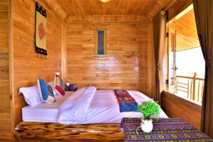 萨帕Hmong Eco Villas的木制客房内的一间卧室,配有一张床