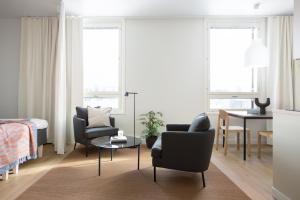 赫尔辛基Noli Malmi的客厅配有两把椅子、一张床和一张桌子