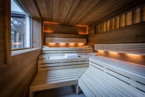 圣安东阿尔贝格"Quality Hosts Arlberg" Hotel zur Pfeffermühle的一间设有木墙、长凳和窗户的桑拿浴室