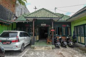 日惹RedDoorz at Mamagayo Inn Yogyakarta的一辆停放在一座带摩托车的建筑前的白色汽车