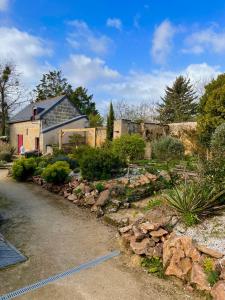 BrignéMaison de campagne, Gîte rouge的一座带房子的院子和一座带岩石的花园
