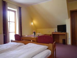 诺因布尔格福尔姆瓦尔德Da`Sporrer Hotel & Wirtshaus的酒店客房设有两张床、一张桌子和一个窗户。