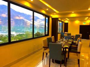 吉尔吉特Avari Xpress Gilgit的一间带桌椅和大窗户的用餐室