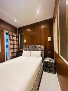 伦敦Cheshire Hotel Central London的一间卧室设有一张大床和木墙