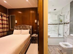 伦敦Cheshire Hotel Central London的卧室配有1张床、浴缸和水槽。