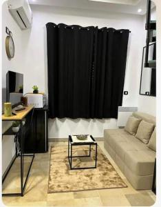 Sidi DaoudAppartement Cosy aux Jardins de Carthage的带沙发和黑色窗帘的客厅