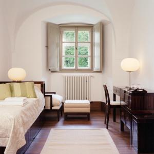 索普隆Sopron Monastery Hotel的一间卧室配有一张床、一张书桌和一个窗户。