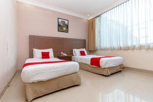 PaalmerahRedDoorz Premium at Hotel Ratu Residence的酒店客房设有两张床和窗户。