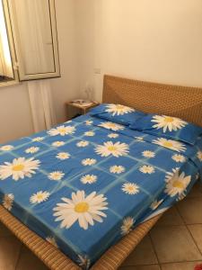兰佩杜萨Attico sul Porto Vecchio - Lampedusa的床上的蓝色棉被和白色花朵