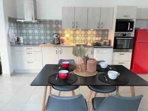 塞兹河畔巴尼奥勒Villa Premium 3 étoiles sur Terrain clos de 300 M2的厨房配有黑色桌椅和红色冰箱。
