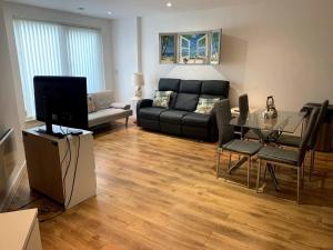 利兹Large Private Flat in City Centre Leeds的客厅配有黑色沙发和玻璃桌