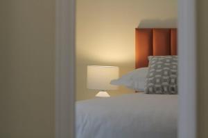罗斯莱尔Burrow Park Holiday Apartments的卧室配有白色的床和灯